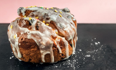 rustic brown biscuit cake with icing. Glaze flows down white smudges with colored powders and sweets close-up. standing on a black surface with icing crumbs. Symbol of Russian Easter. Easter card