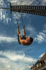 outdoors portrait of young attractive and athletic man practicing aero yoga workoutat the beach...