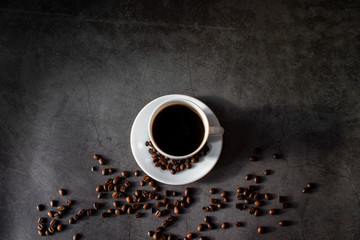 White cup with saucer and coffee beans, aromatic, hot coffee on a dark flat lay