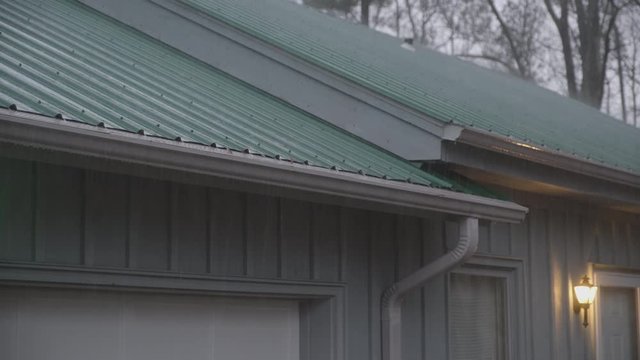 Heavy rain falls on a metal roof, collecting and safely flowing through a maintenance free gutter system.