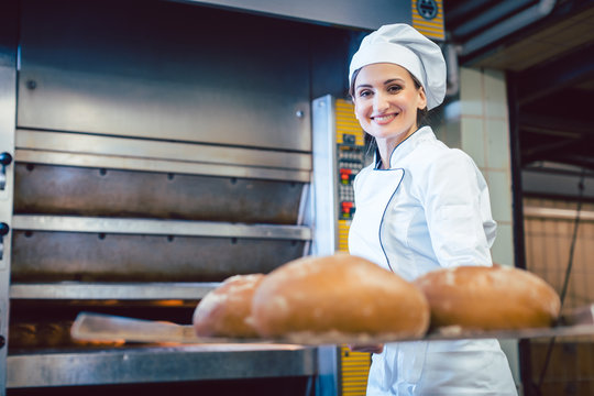Baker woman showing freshly baked bread on shovel