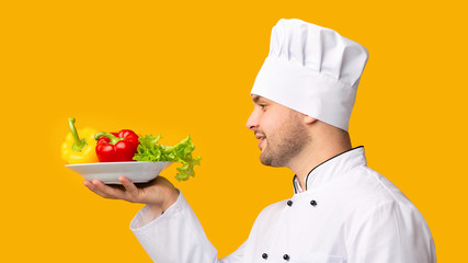 Cook Man Holding Plate With Vegetables In Studio, Side-View, Panorama