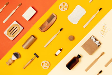 Ecological accessories for body care: natural sponges, wooden comb, shaving brush, glass bottle with lotion, soap, toothbrushes and craft tube located on tricolor yellow background.