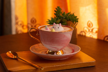 Sugar cube in a cup of hot cappuccino coffee on the wooden table.