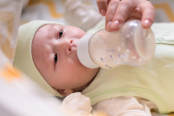 young mother feeds her baby milk from a bottle