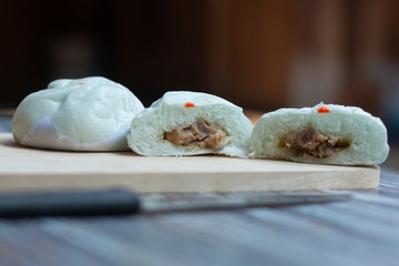 Steamed pork bun in wooden butcher on the wooden table.
