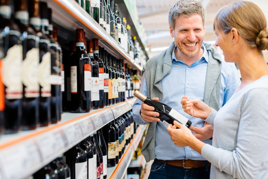 Woman And Man Buying Wine In Supermarket