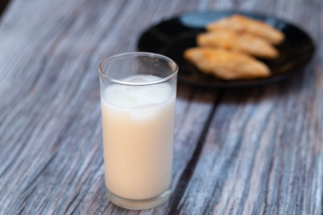 Ice milk with donut and bread on the wooden background.