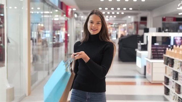 girl goes with packages after shopping in mall
