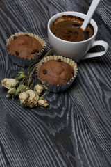 Fototapeta premium Coffee in a white cup. Nearby are muffins, and a dried rose of beige color. On brushed pine boards.