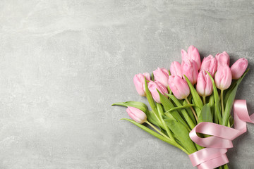 Tulips with ribbon on grey background, top view