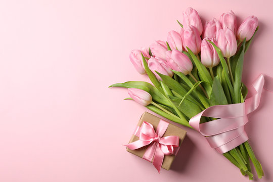 Bouquet of tulips and gift box on pink background, space for text