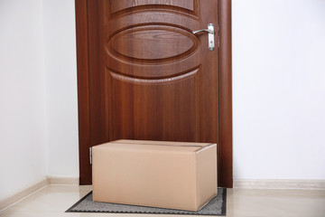Cardboard box on rug near door. Parcel delivery service