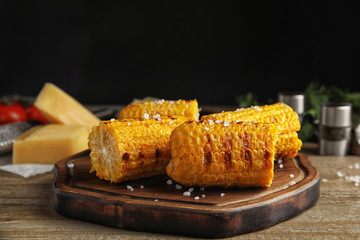 Delicious grilled corn cobs on wooden table