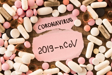 Coronavirus. 2019-nCoV. Scattered pills and the inscription CORONAVIRUS on a piece of paper on a wooden background. The concept of virus protection. Selective focus.