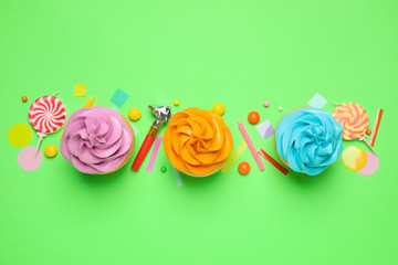Flat lay composition with colorful birthday cupcakes on green background