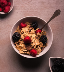 A great breakfast of cereals, raspberries and blackberries. On wooden background. Square format.