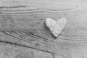 Snowy heart melts on a wooden table. Heart shaped snowball on a wooden kitchen cutting board. Ice in frosty weather. Melted water in the form of drops. Love on valentine's day concept