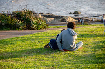 couple sitting on the grass contemplating the lake in front of