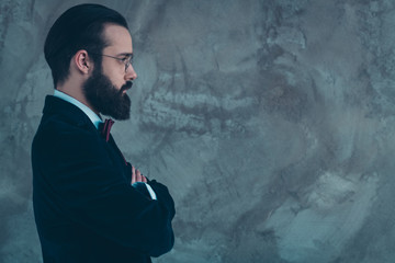 Close-up profile side view portrait of his he nice attractive representative serious bearded guy wearing velvet tux folded arms copy space isolated over gray concrete industrial wall background