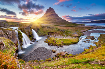 Colorful sunrise on Kirkjufellsfoss waterfall. Amazing morning scene near Kirkjufell volkano, Iceland, Europe. A famous tourist attraction near the city of Grundarfjordur. Travel concept background.