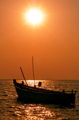 Fototapeta na wymiar Silhouette of Small Wooden Boat Floating on the Sea