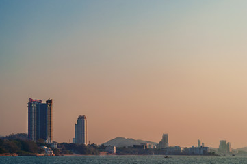 The buildings and skyscrapers on the sea shore in dramatic blue and red sky, minimalist view from the sea.