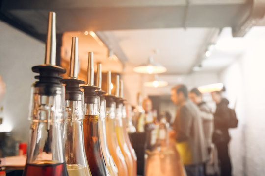 Glass bottles with dozers or dispensers for pouring alcohol cocktails, beverages or drinks in bar, nightclub, restaurant or pub, with blurred background (selective focus, shallow DOF)