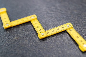 Folding zig zag ruler. Measuring tape folding yellow open in zigzag tips on a workbench. Measuring...