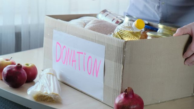 Man putting food into Donate Box, donation and charity concept. Donations to the needy and the starving