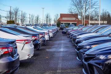 View of rows of various colored new cars in a parking lot with a access space between them © ALAN