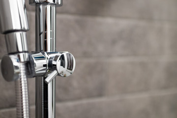 detail of chrome shower supplies and taps with tiles in the background