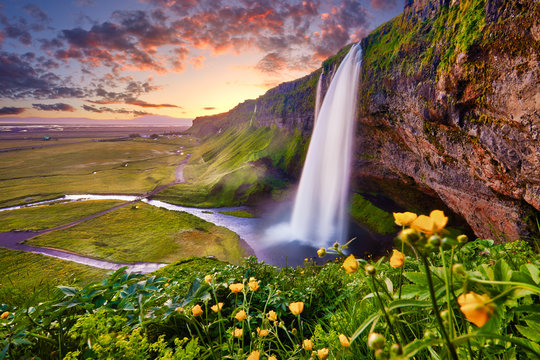 Incredible sunset on Seljalandsfoss. One of the most beautiful waterfalls on the Iceland, Europe. Popular and famous tourist attraction summer holiday destination in on South Iceland. Travel postcard.