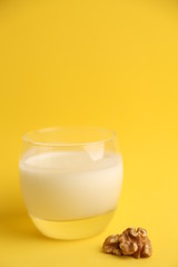 glass of walnut milk in color background
