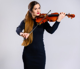 Portrait of a pretty brunette musician girl with a smile in a black dress on a white background...
