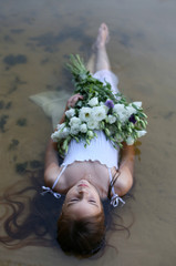 vertical photo of a ten-year-old girl in a white sundress lying in the water