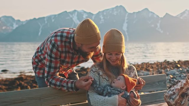 Happy family mother and father playing with baby travel vacations outdoor parents with infant child healthy lifestyle mountains landscape 