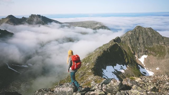 Woman hiking in mountains with backpack adventure travel healthy lifestyle activity girl happy raised hands summer vacations trekking in Norway over clouds