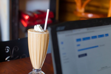 Ice Coffee with cream near a laptop in a coffee shop