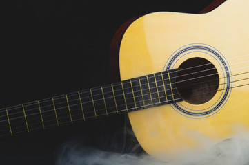 Obraz na płótnie Canvas Acoustic guitar in smoke on the black background. musical instrument