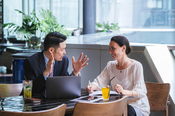 Two confident business people talking and smiling. Business partners having a successful meeting at...