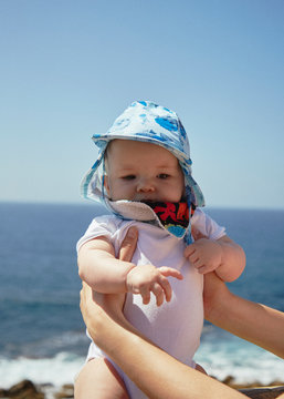 Baby being held in font of the ocean