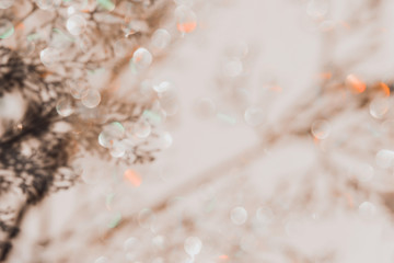 Grey botanical shadows of branches on beige wall background with golden bokeh. Abstract background.