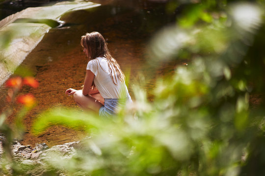 women crouching by a river