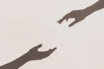 Graue Schatten von Händen, die sich an der Wand berühren. Abstrakter unscharfer Effekt. © Ira_Shpiller