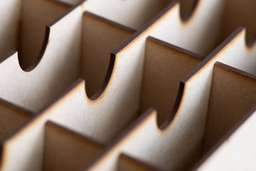 Selective-focus abstract of a wooden packing trellis showing regular lines, patterns and shadows in pastel brown and beige shades of colour.