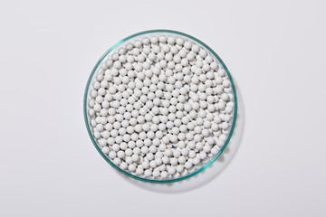 Top view of white decorative beads inside laboratory glassware on grey background