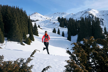Trail runner woman running in winter mountains trail on snow. 