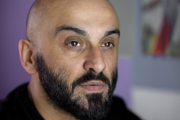 Close-up portrait of a bearded bald man thinking about something.
