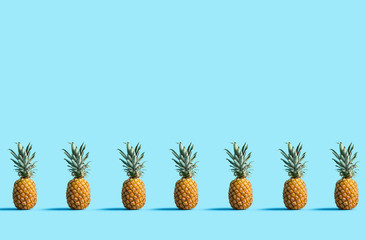 Many pineapples on a solid color background